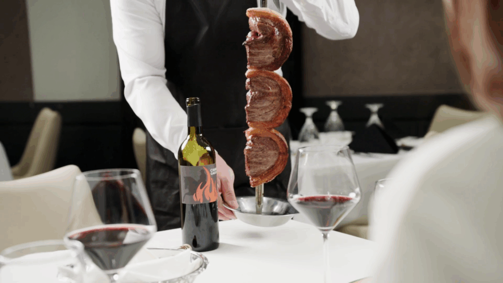 Gaucho carving fire roasted Picanha tableside with red wine served at Chama Gaucha Brazilian Steakhouse