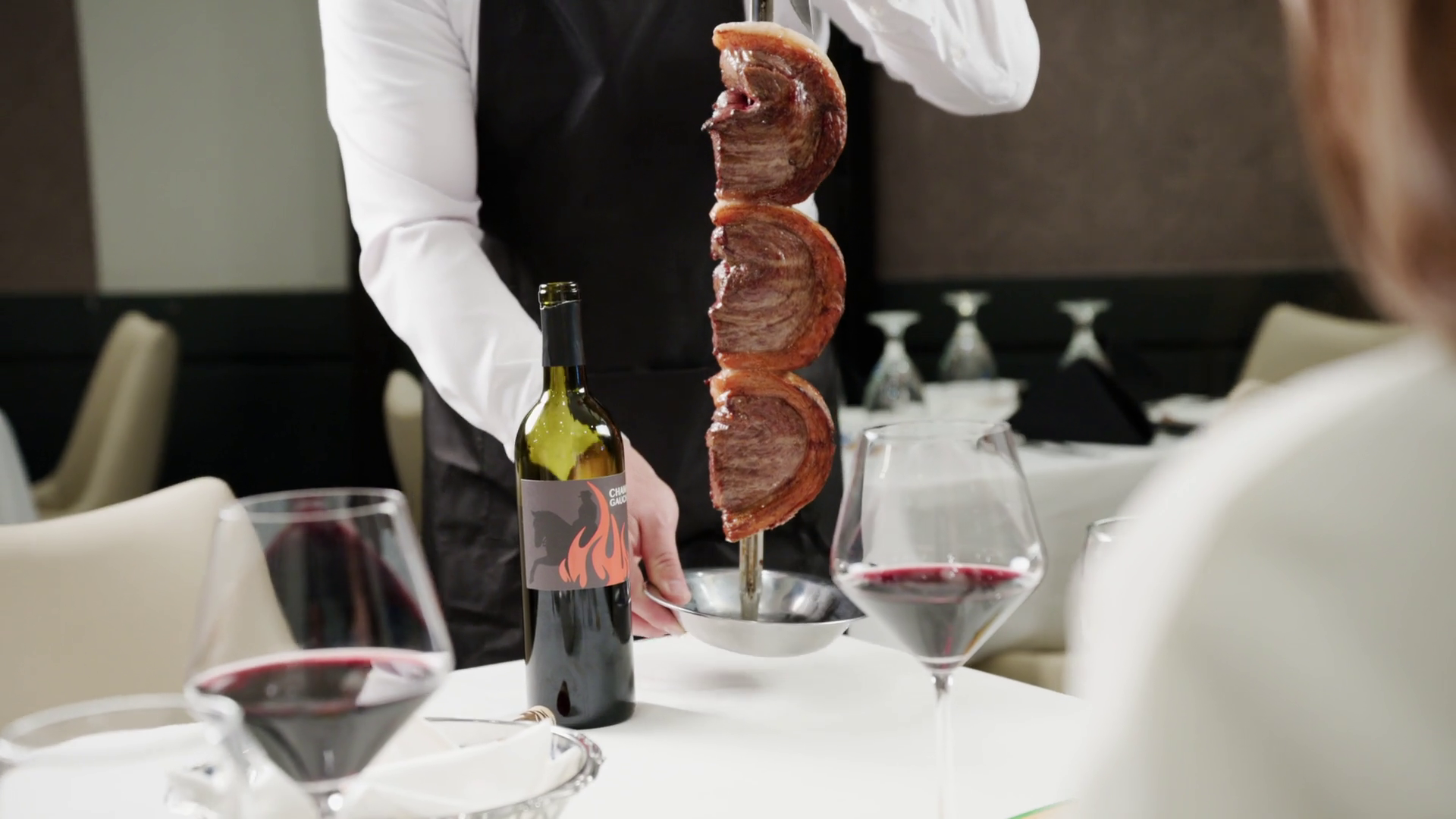 Gaucho carving fire roasted Picanha tableside with red wine served at Chama Gaucha Brazilian Steakhouse