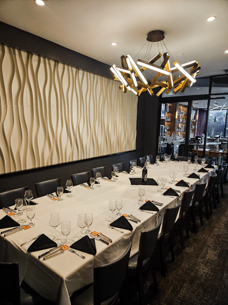 Houston private dining room with long banquet table, black chairs, modern chandelier, and elegant interior at Chama Gaucha