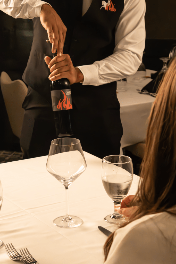 Sommelier opening a bottle of red wine tableside at Chama Gaucha Brazilian steakhouse fine dining restaurant