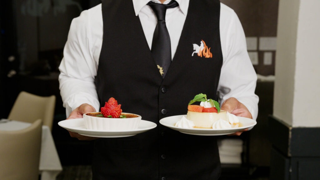 Chama Gaucha Brazilian Steakhouse server presenting crème brûlée and flan desserts at the table
