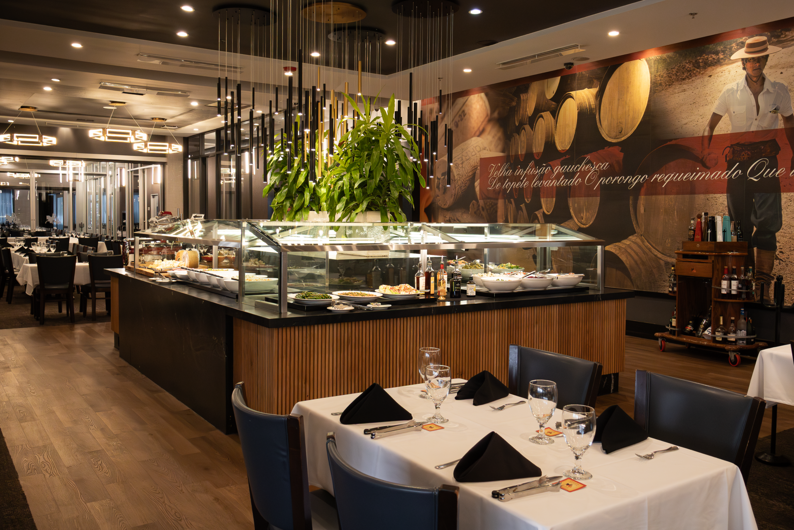 Gourmet salad bar with glass display case and fresh offerings at Chama Gaúcha Brazilian Steakhouse Houston, with a gaucho mural on the wall
